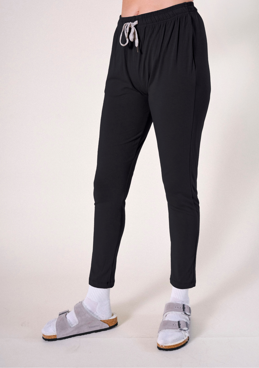 Side angle shot of the black tapered Poplinen Toni PJ Pant showcasing the cinched waistband and relaxed leg fit.