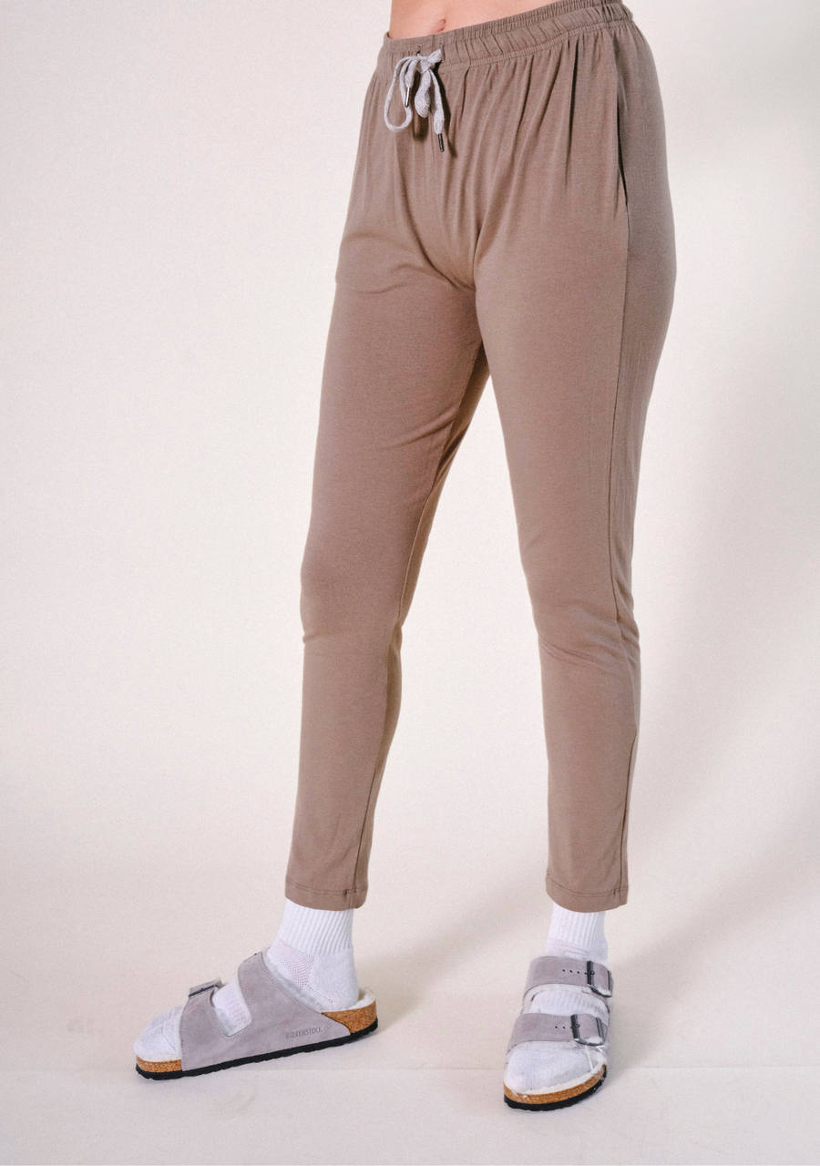 Side angle view of the olive-brown Poplinen Toni PJ Pant showing the elastic drawstring waist and tapered leg silhouette.