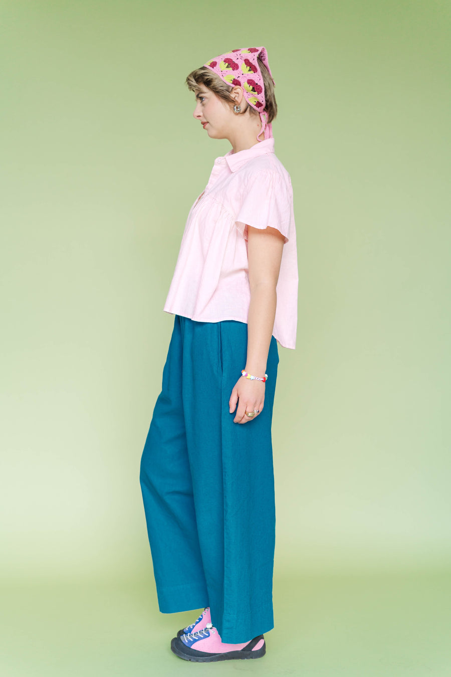 Side view of a pink custom-dyed linen shirt featuring a relaxed, flowy drape and chest-seam detailing. Shown on a model wearing the size-inclusive Button Mushroom Top by Nettle Studios.