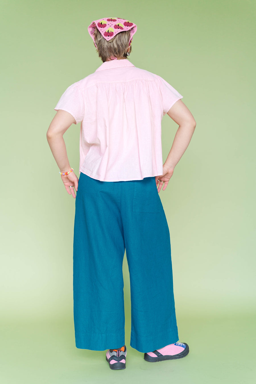 Bkac view of a pink custom-dyed linen shirt featuring a relaxed, flowy drape and chest-seam detailing. Shown on a model wearing the size-inclusive Button Mushroom Top by Nettle Studios.