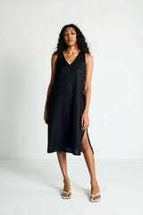 Full-length front view of a model presenting the minimalist black Hemp Noir dress, showcasing its easy, edgy cut and loose silhouette styled with casual white thong sandals.