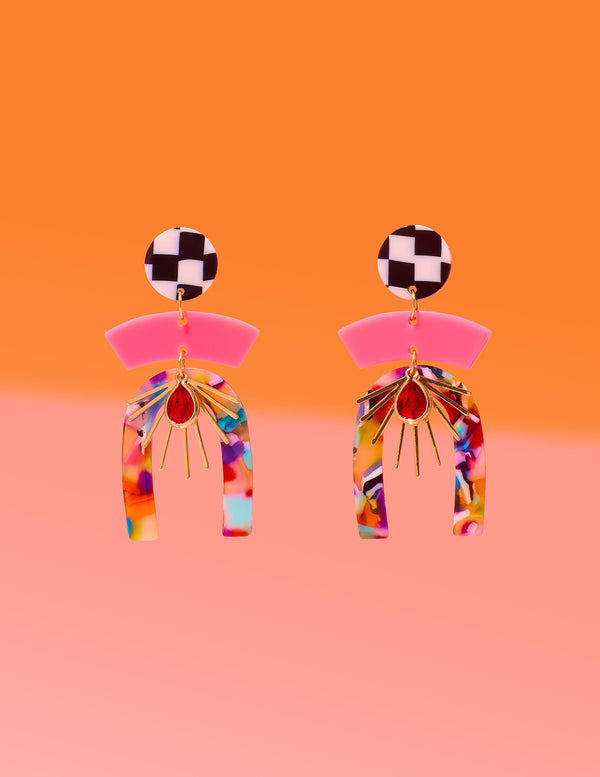 Tribe and Temple Confetti Multi Mixed Media Earrings featuring a black and white checkered stud, pink arc, and a multicolored confetti resin arch with a gold-plated sunburst and red teardrop center on an orange and pink background.