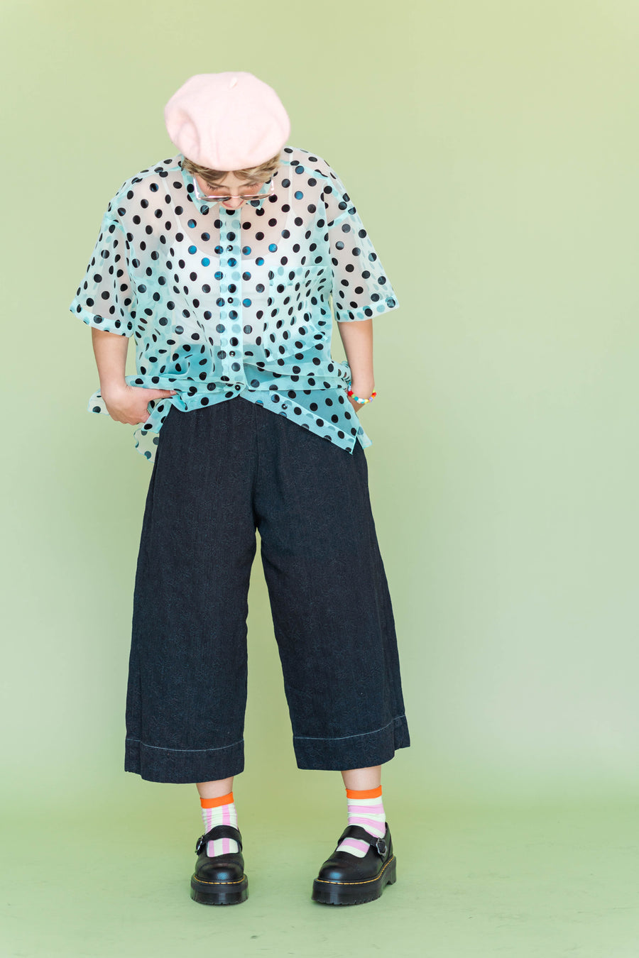 Front view of the Nettle Studios Black Daisy Denim Mid Easy Pant featuring an oversized cropped wide-leg fit, paired with a blue sheer polka dot shirt.
