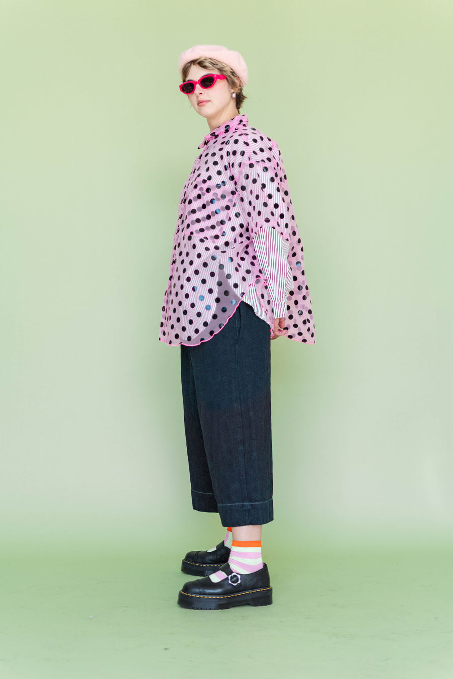 Side profile view of the Nettle Studios Black Daisy Denim Mid Easy Pant showing the relaxed silhouette, styled with a pink sheer polka dot top and sunglasses.