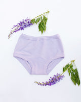 Flat lay view of the Thunderpants US Wisterial Girl purple-grey organic cotton briefs styled with wisteria flowers on a white background.