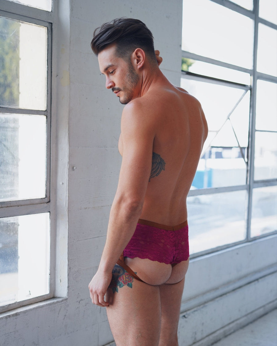 Rear profile view of a male model looking down while wearing  lace cantiqLA Bandage Boyshorts.