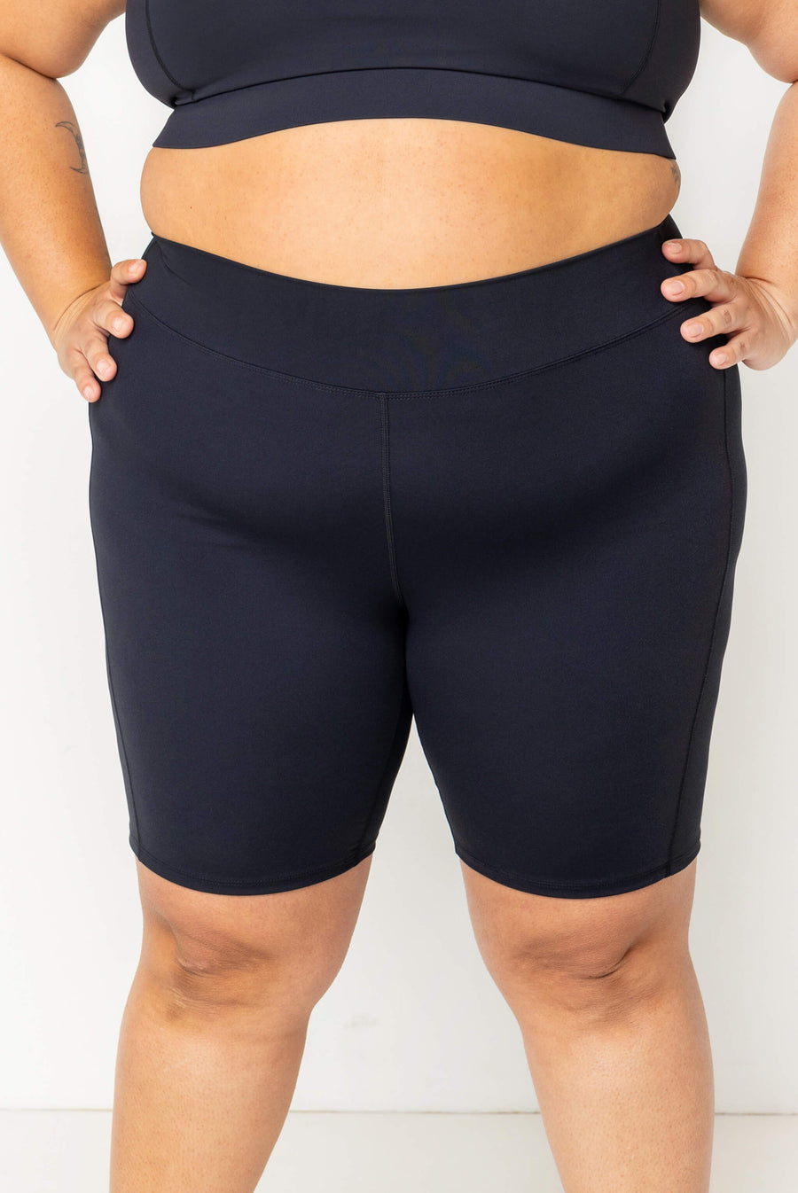 Front close-up view showing the high waistband and 9-inch inseam coverage of the black Superfit Hero swim shorts.