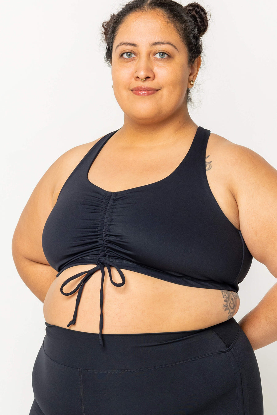 Front view of a model posing in the black Superfit Hero cinched bikini top paired with matching high-waisted black swim bottoms.
