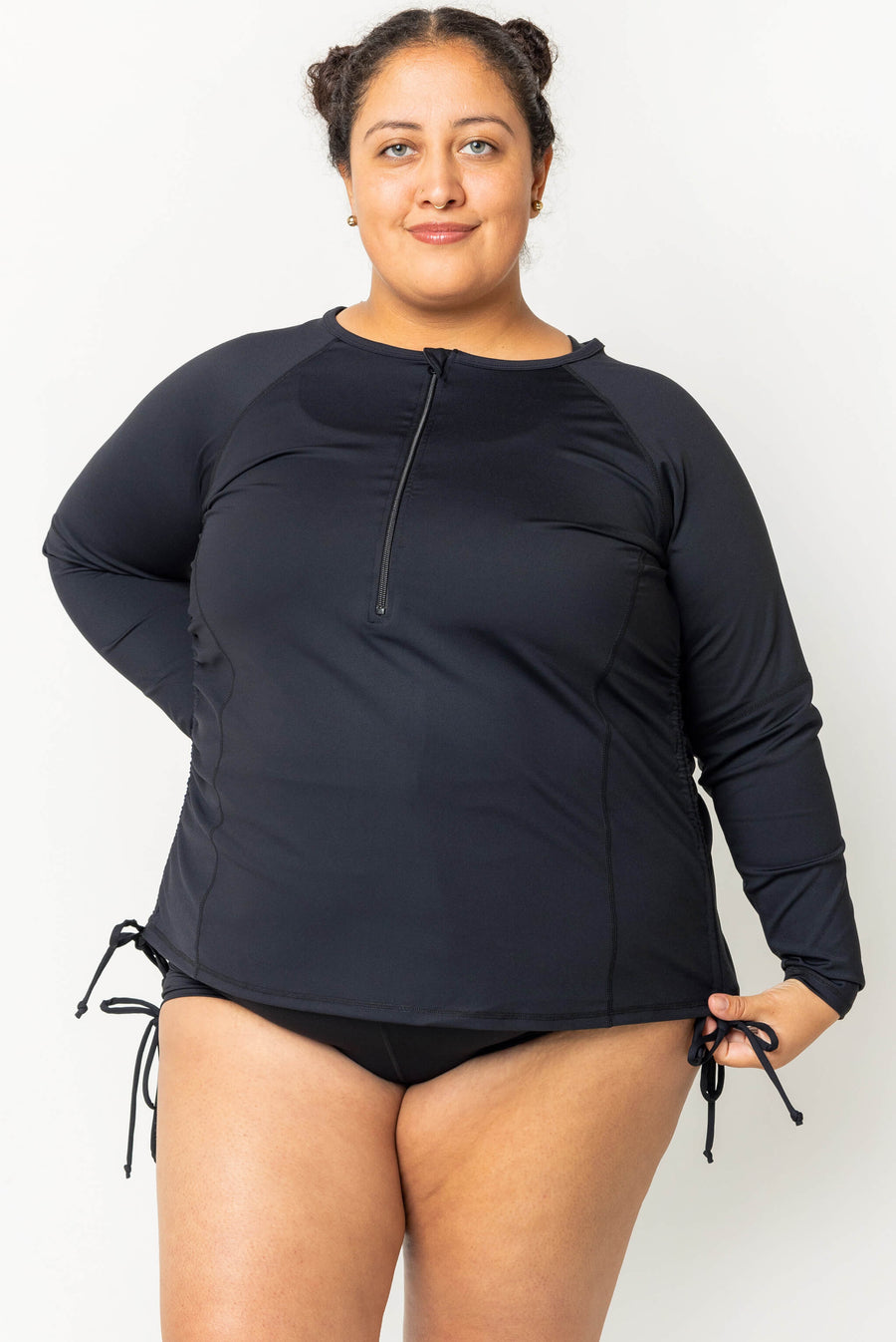 Front view of a model posing in the black Superfit Hero long sleeve rash guard with high half-zip neck paired with black swim bottoms.
