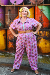 Full-length portrait of a model showcasing the short sleeves and wide-leg fit of the Blue Platypus Cheeky Tiki Monkeys Jumpsuit in Magenta styled with a brown belt.