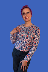 Studio portrait of a model with short purple hair wearing the Blue Platypus Fruit Picnic Pullover in Blueberry against a blue backdrop.