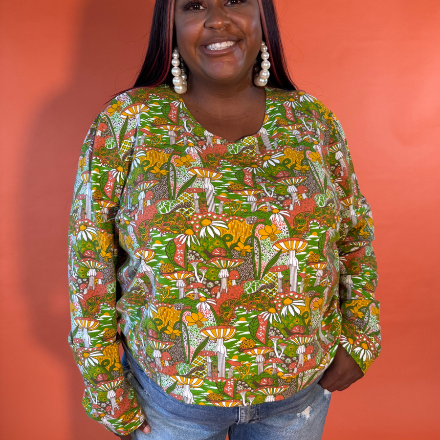 Studio portrait of a plus-size model showcasing the relaxed silhouette of the Blue Platypus Magnificent Mushroom Pullover in Olive.
