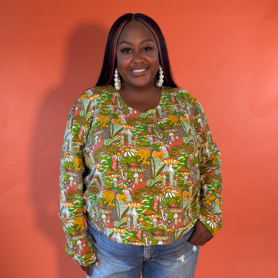 Plus-size model smiling while wearing the size-inclusive Blue Platypus Magnificent Mushroom Pullover in Olive.