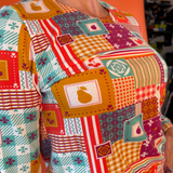 High-resolution close-up of the French terry fabric displaying fruit and geometric tablecloth patchwork graphics.