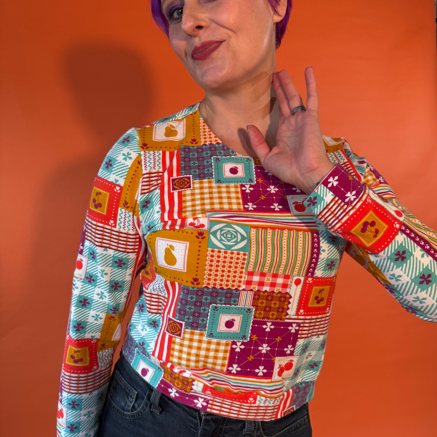 Medium close-up view showing the crew neckline and vintage tablecloth pattern on the Blue Platypus Patchwork Pullover in Magenta.