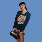 Solo studio shot of a model with dark bangs wearing the Blue Platypus Wacky Owls Pullover in Midnight Blue with a plaid mini skirt.