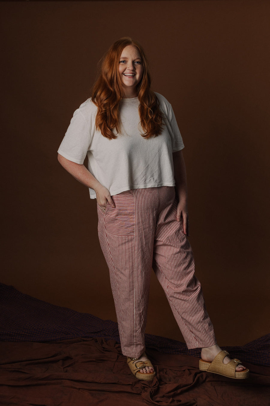 Full-length view of Kendra wearing size 2XL Emil Taper Pant in Red Stripe Workcloth paired with a white top and sandals.