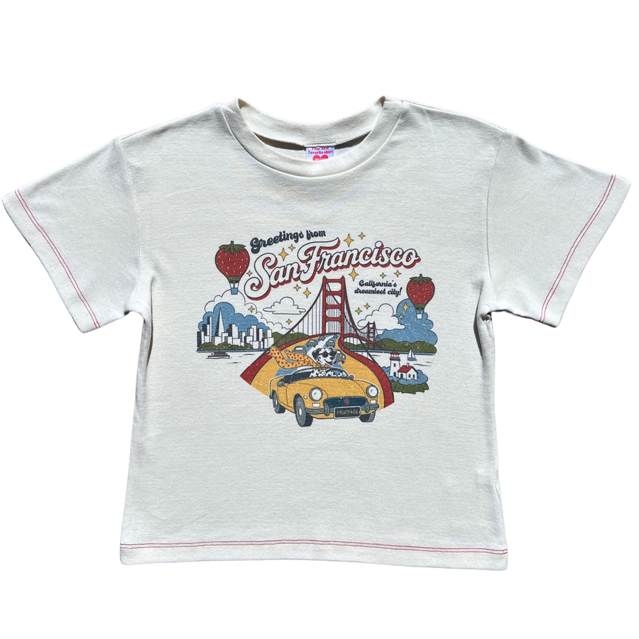 Front product flat lay of the off-white Greetings from SF Baby Tee featuring Golden Gate Bridge artwork and red contrast stitching
