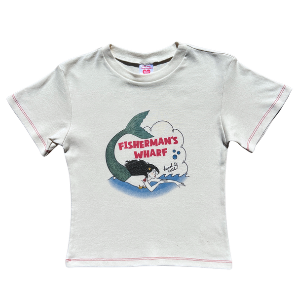 Front flat lay view of the Fruit Face Hard to Catch Off-White Baby Tee featuring a Fisherman's Wharf mermaid graphic and red contrast stitching.