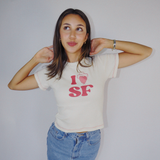 Studio portrait of a model looking up while wearing the off-white Fruit Face I Heart SF Baby Tee with red stitching.
