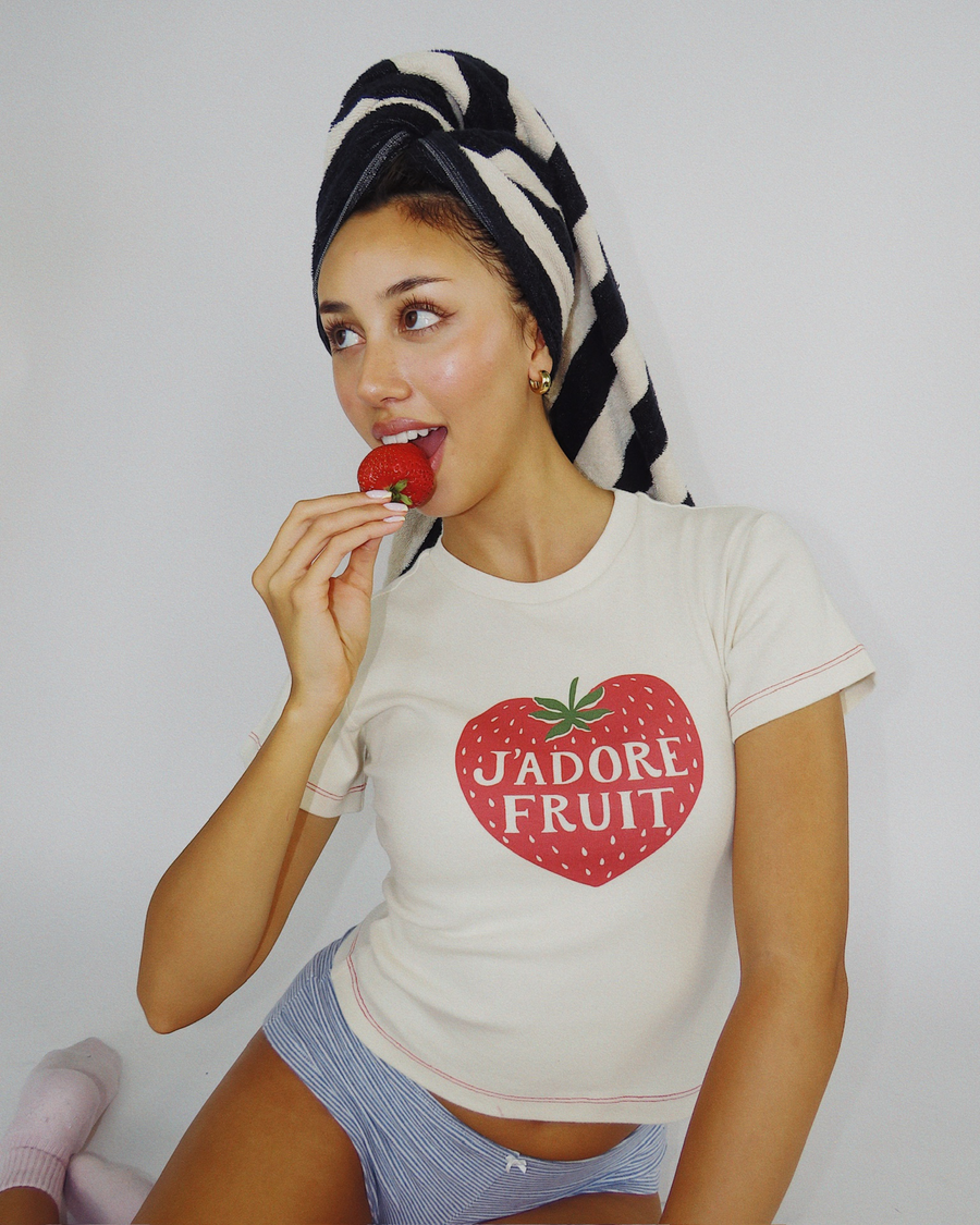 Playful studio pose of model Dorothy in the organic cotton Fruit Face J'Adore Fruit Baby Tee.