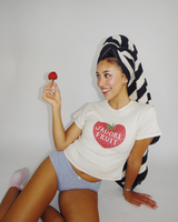 Model Dorothy wearing the Fruit Face J'Adore Fruit Baby Tee while posing with a strawberry and head towel.