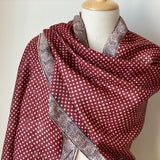 Deep red handwoven Tassar silk stole with off-white polka dots draped elegantly around a mannequin shoulder.