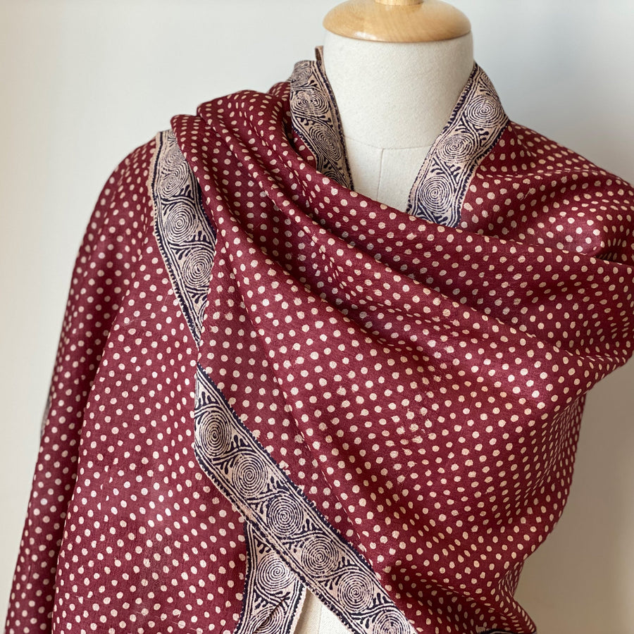 Deep red handwoven Tassar silk stole with off-white polka dots draped elegantly around a mannequin shoulder.