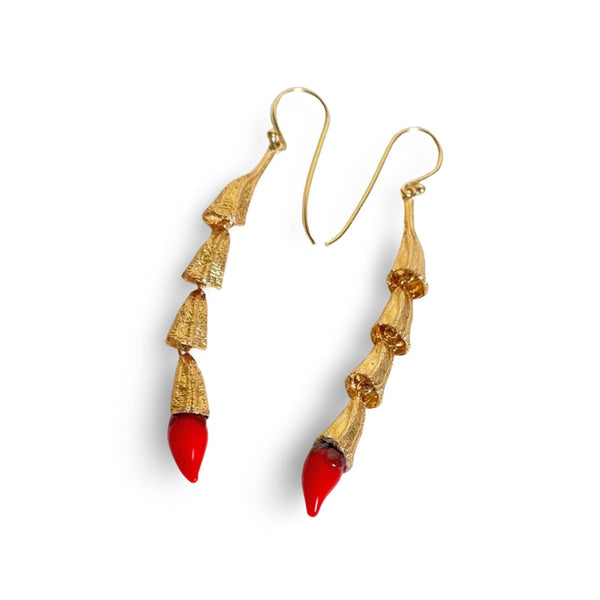 Angled studio view showing the articulated gold pod links and red glass chili details on the MIRCHI drop earrings.
