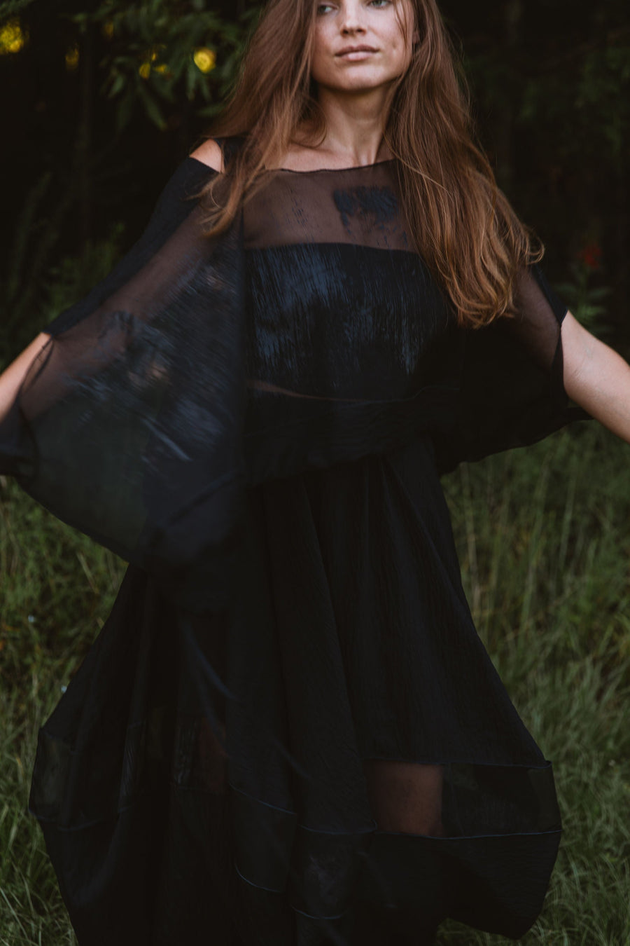 Close-up of model twirling in the black modal-nylon Bellows Skirt showcasing the sheer silk organza panel and fluid drape.