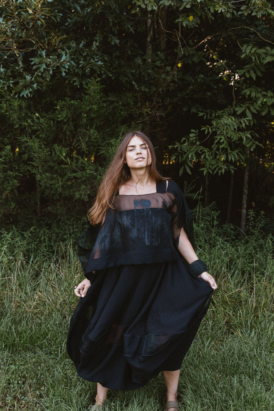 Model wearing the Hand-Painted Silk & Modal Bellows Skirt standing outdoors against a lush forest backdrop.