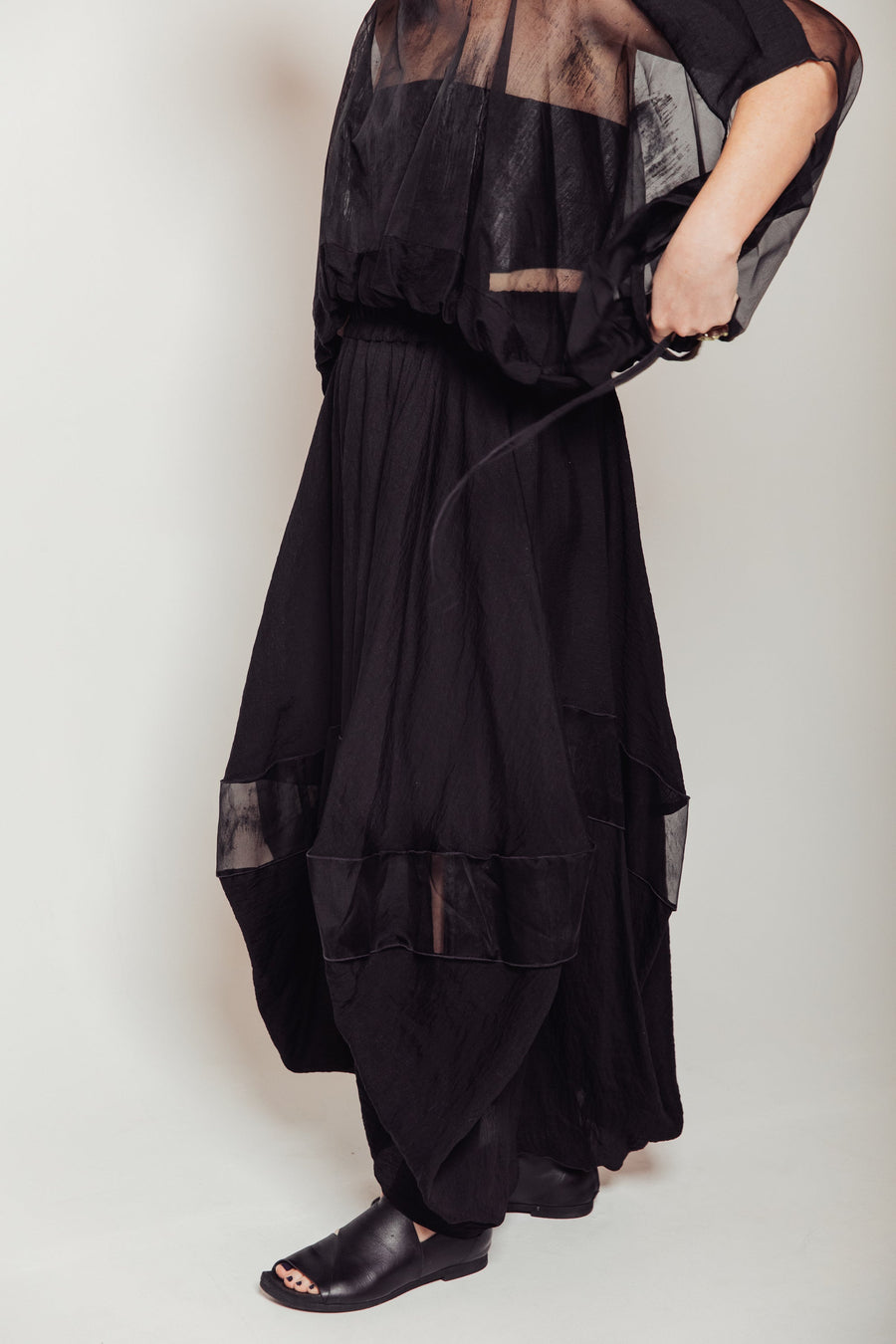 Side profile highlighting the architectural balloon silhouette and exposed tonal rolled serging on the Bellows Skirt.