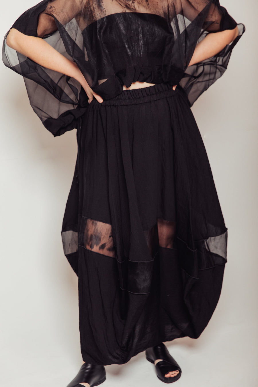 Front view of model wearing the black Hand-Painted Silk & Modal Bellows Skirt displaying the sheer dry-brushed organza window panel