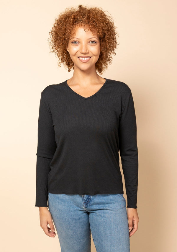 Front studio view of a model wearing the black Hedy Ribbed Modal V-Neck Long Sleeve Tee paired with blue jeans.