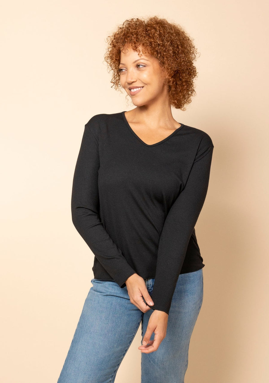 Three-quarter angle portrait of a model wearing the black Hedy Ribbed Modal V-Neck Long Sleeve Tee.