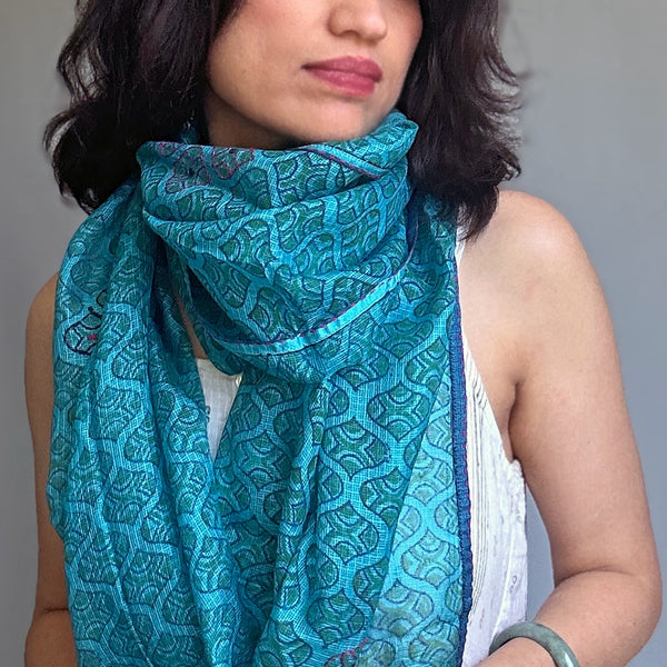 Medium portrait of a woman wearing the turquoise Kota silk scarf draped loosely over a white tank top