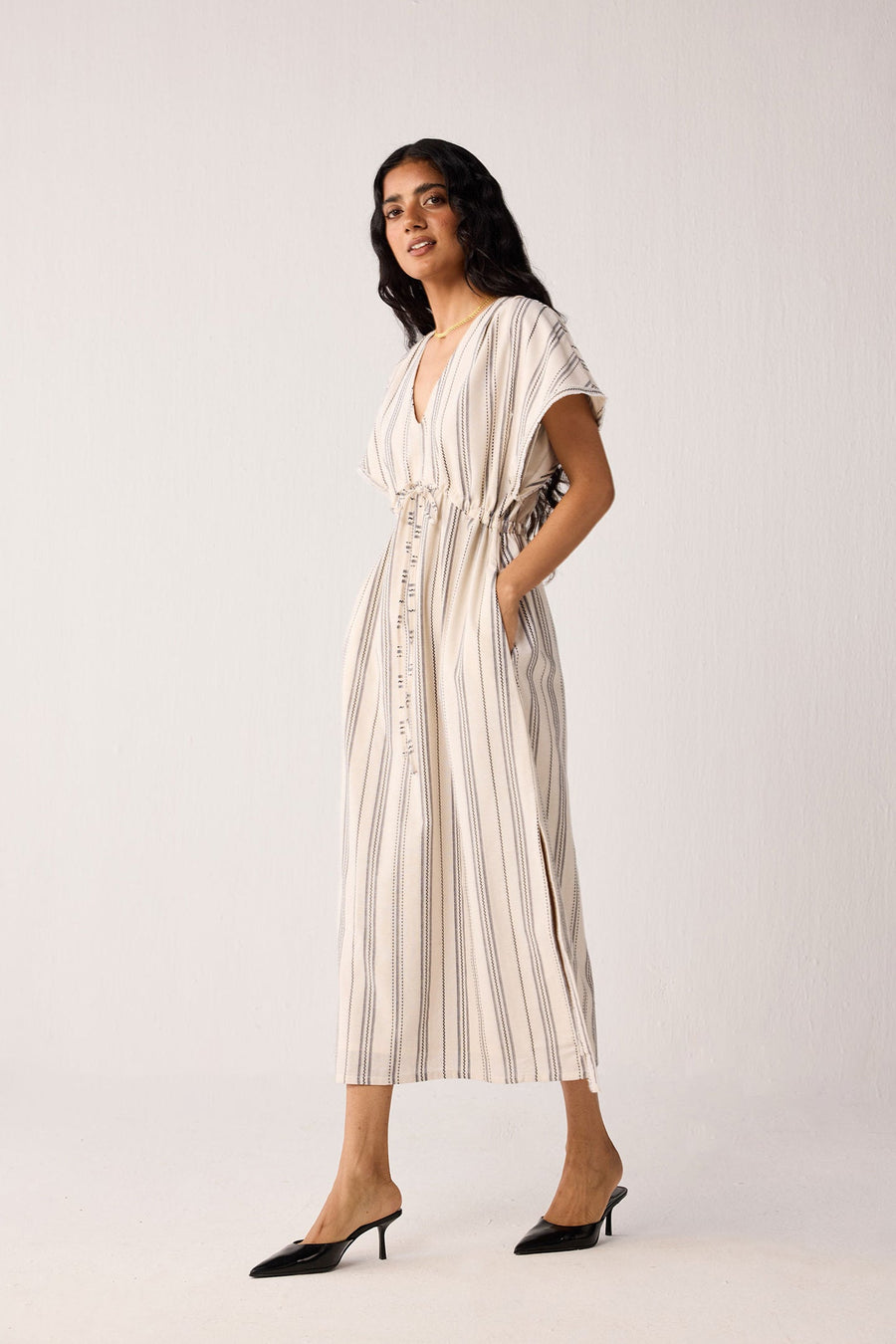 Woman wearing a white and beige striped dress against a white background