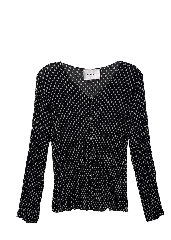 Studio flat lay product view of the Baacal Maya Hand-Pleated Cardigan in black and white polka dot print featuring a V-neckline and Mother of Pearl buttons.