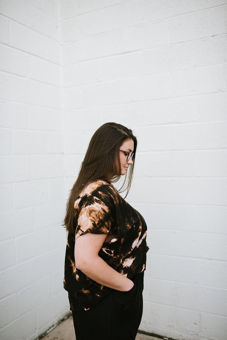 Side profile shot of a model wearing the short-sleeved Megan-Ilene Zero Waste Silk Market Top tucked into black trousers.