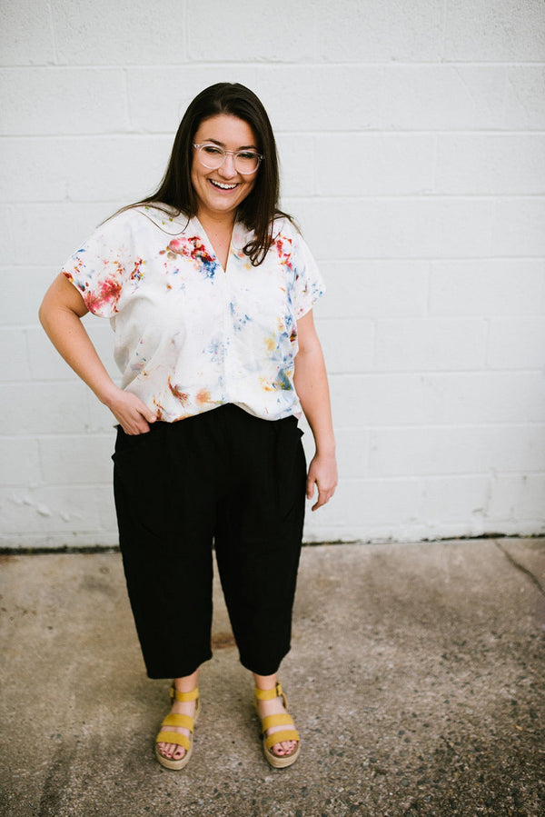 Model wearing the hand-dyed Megan-Ilene Zero Waste Silk Market Top with black crop pants against a white brick wall