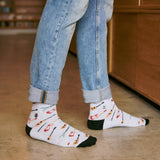 Standing perspective shot of someone wearing cuffed jeans and Conscious Step guitar print socks indoors.