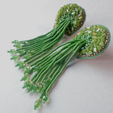 Front view of the green Fyoli Fyoli TORTULA Moss Hand Embroidered Earrings, featuring intricate glass beadwork on a velvet backing with a long, flowing beaded fringe against a white background.