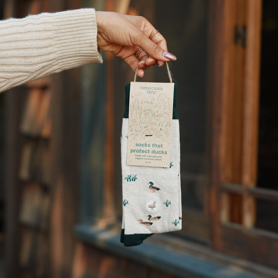 Person holding a packaged pair of Conscious Step Socks That Protect Ducks .
