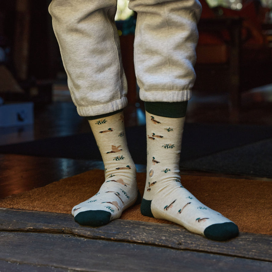 Standing view of someone wearing cuffed grey sweatpants and Conscious Step mallard duck socks indoors.