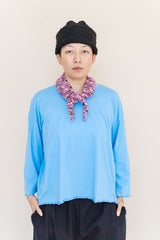 Front view of model Madison wearing the bright blue Nettle Studios Neptune Base Layer with lettuce hem and a knit scarf