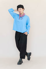 Full-length studio portrait of model wearing the bright blue Nettle Studios Neptune Base Layer styled with black boots and beanie.