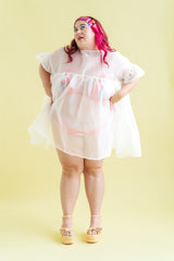 Full-length studio portrait of model in the sheer white Nettle Studios Silk Organza Mini Mushroom Dress with hands on hips.