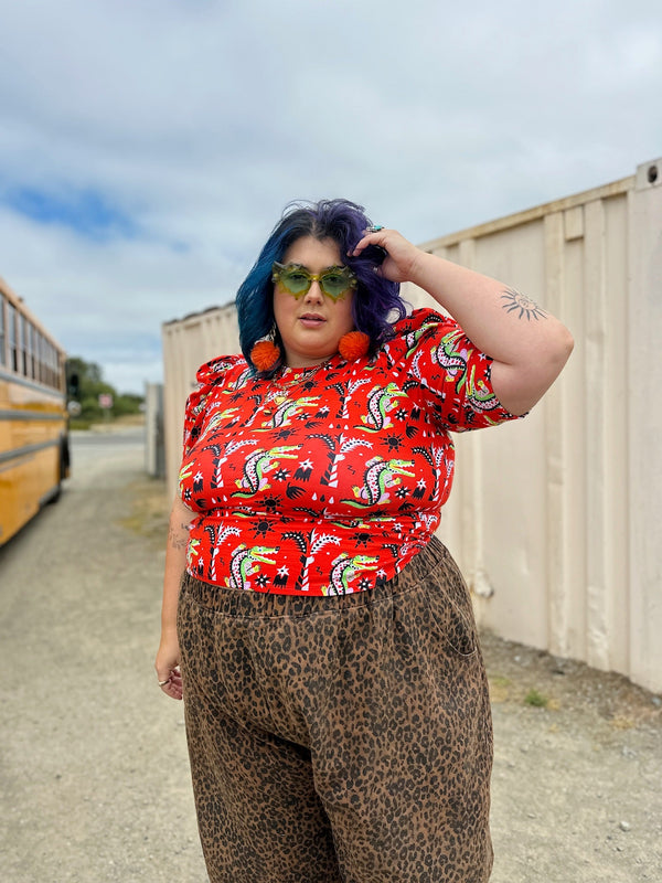 Angelina wearing size 4X NOOWORKS Puff Top in red Crocodilo print by Camila Leão with animal print pants and green sunglasses outdoors