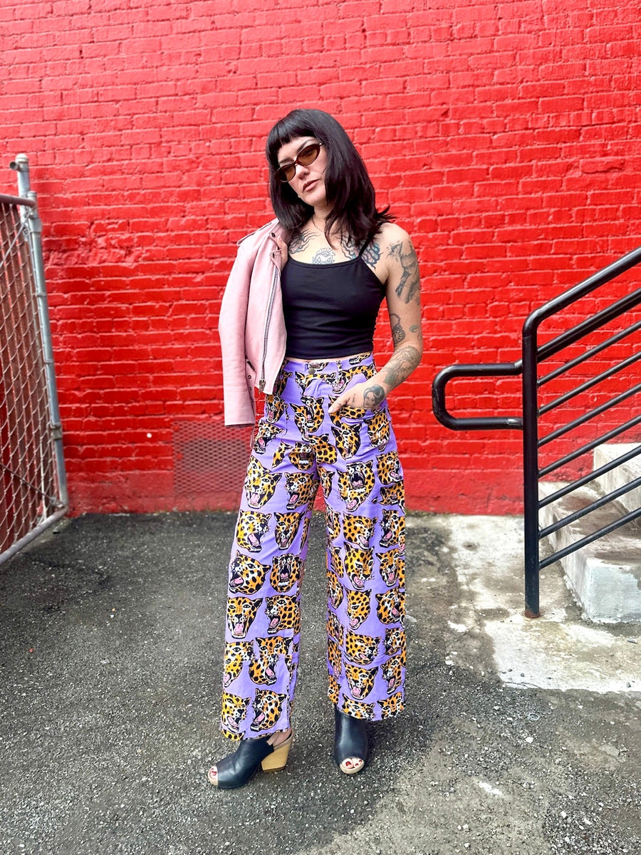 Full-length street portrait of Mia wearing size Small NOOWORKS Skater Pant in purple Cheetah Head print by Robin Eisenberg.