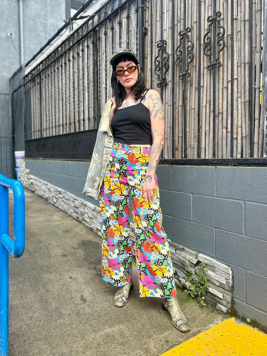 Full-length street portrait of Mia wearing size Small NOOWORKS Skater Pant in colorful Cosmic Floral print by Elizabeth Olwen paired with snakeskin boots